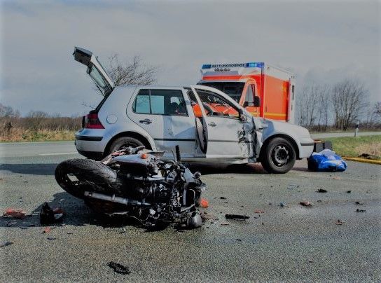 motorcycle lying on the ground after crashing into a car